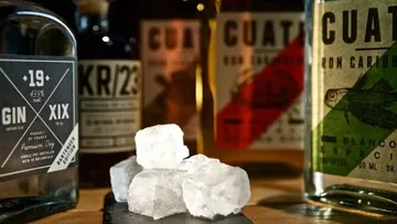Eiswürfel auf der Oberfläche, Spirituosenflaschen im Hintergrund.