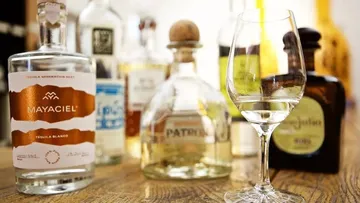 Various tequila bottles and glass on table.