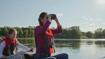 Frau und Mädchen auf dem Boot mit Fernglas.