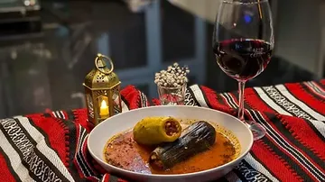 Stuffed vegetables in sauce with wine and candle.