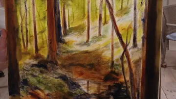 Hand holding a forest landscape painting.