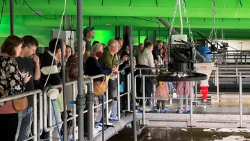 Gruppe von Personen, die eine Fischzuchtanlage beobachten.