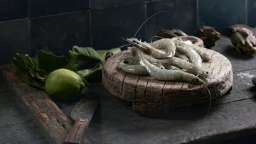 Raw shrimp on wooden board with lime.