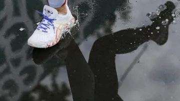 Laufschuh tritt auf einer Wasserpfütze auf.