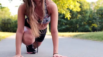 Woman in running start position on path.