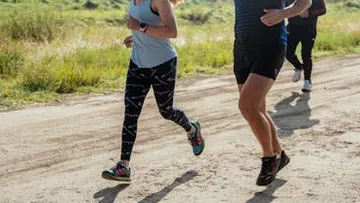 Two people running on a dirt path.