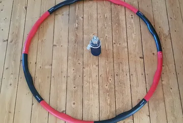 Hula Hoop umschließt die Wasserflasche auf dem Holzboden.