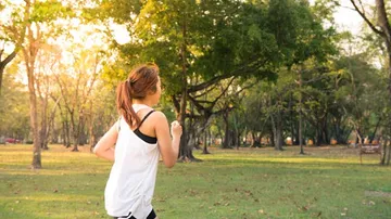 Frau joggt in einem sonnigen Park.