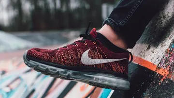 Red Nike shoe on colorful graffiti wall.