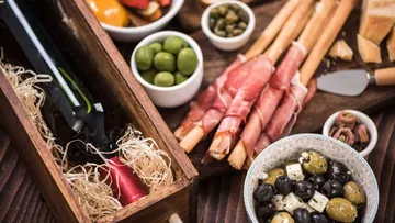 Wine, olives, breadsticks, and cheese on table.