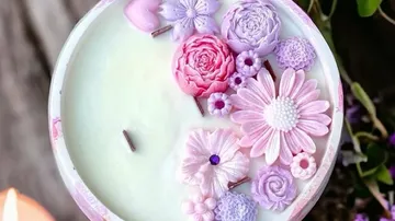 Decorative candle with floral designs in pink and purple.