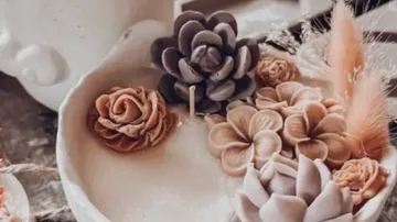 Decorative candles shaped like succulents in dish.