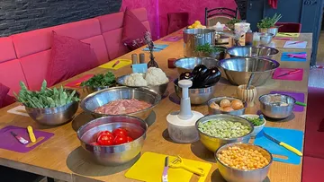 Tisch mit Schalen mit Gemüse und Zutaten.