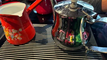 Rote und metallene Teekannen auf einer gerippten Matte.