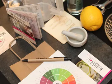 A notepad and accessories lie on a table with ingredients.