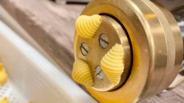 Pasta extruder forming spiral pasta shapes.