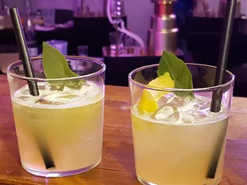 Two cocktails with ice cream, napkin and decoration on bar counter.