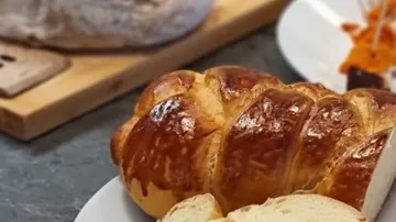 Shiny braided bread loaf on white plate
