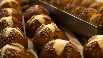 Freshly baked pretzel buns on tray.