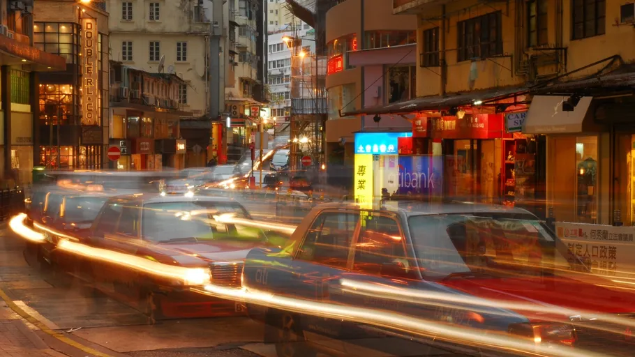 Blurred cars and neon lights on city street.