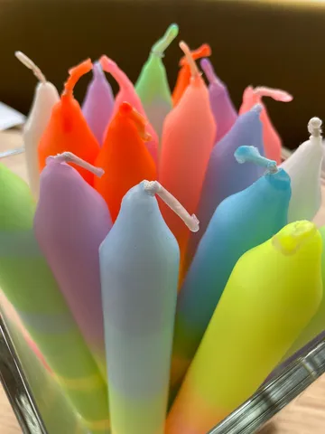 Colorful candles in a glass container.