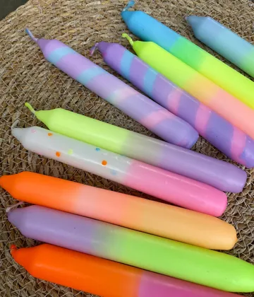 Colorful ombré candles on woven surface.