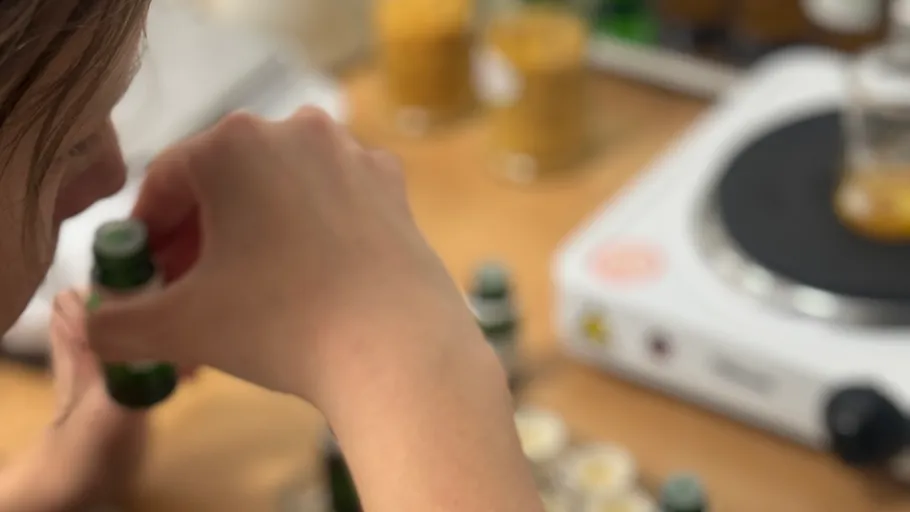 Person smelling small bottle near a hotplate