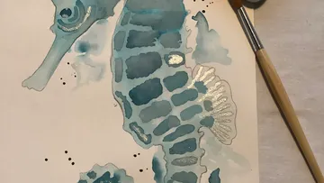Watercolor seahorse painting with paint palette.