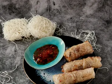 Fried spring rolls with dipping sauce on plate.