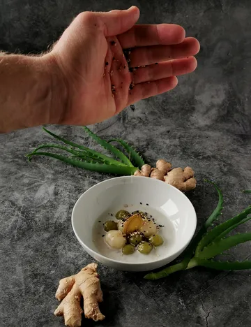 Hand sprinkling seeds over plated dish.
