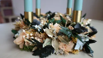 Floral wreath with teal candles on table.