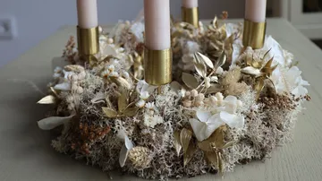 Decorative wreath with four candles on table.