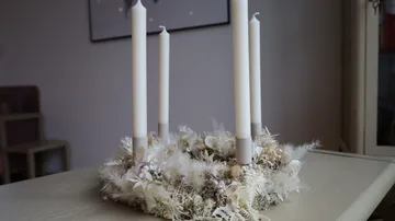 Four white candles in decorative wreath.