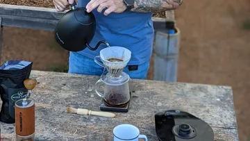 Person, die im Freien Kaffee mit Übergießeinrichtung zubereitet.