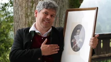 Man holding framed portrait outdoors.