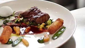 Gourmet steak dish with vegetables and sauce.