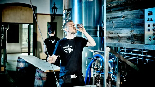Der Mann trinkt Bier in einer Brauerei.
