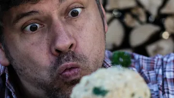 Man making surprised face at food, wood background.