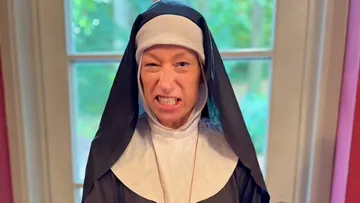 Person in a nun costume, winking indoors.