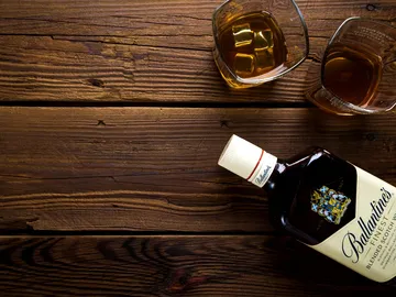 Whiskey bottle is lying on the table, two glasses next to it.
