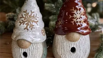 Zwei Gnomen-Vogelhäuschen aus Keramik mit Schneeflockenhüten.