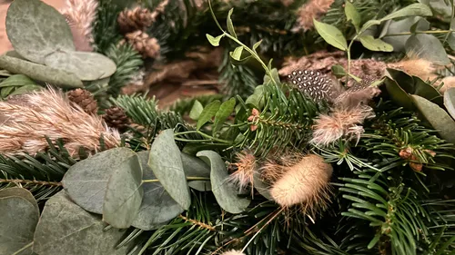 Green foliage with dried plants and feathers.