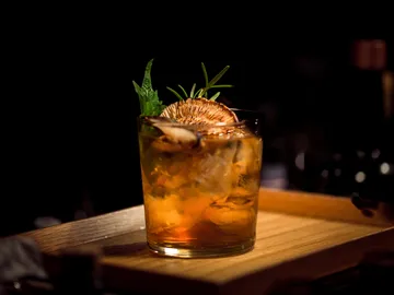 Ein Cocktail mit dekorativen Kräutern auf einem Tablett.