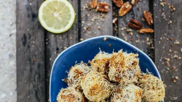Kataifi rolls on blue plate, lemon, pecans.