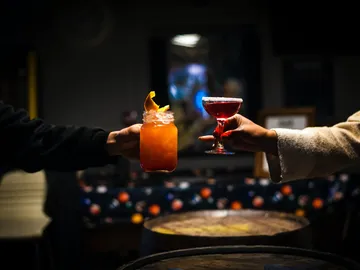 Getränke werden zwischen zwei Personen in einer Bar übergeben.