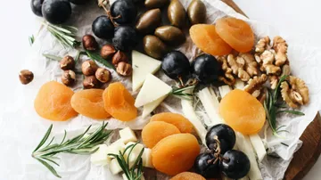 Fruit, cheese, and nuts on a wooden board.