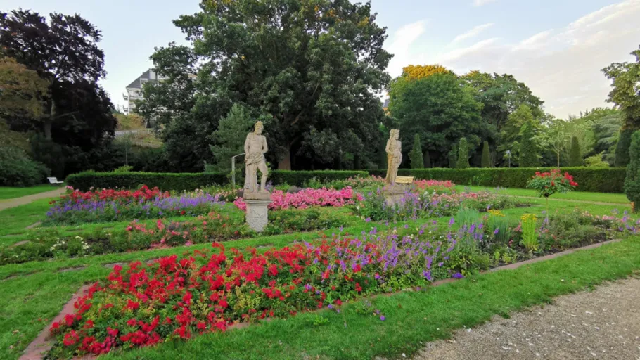Statues in a colorful flower garden.