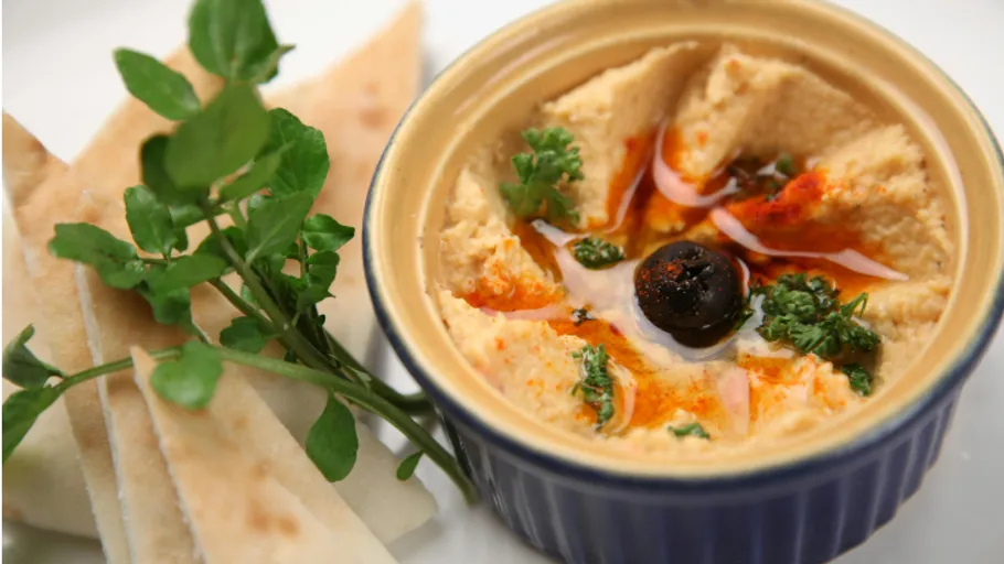 Bowl of hummus with pita and olives.