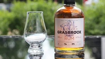 Grasbrook Rumflasche und Glas im Freien.