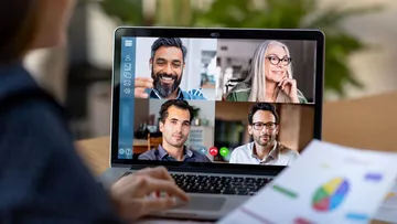 Four people video conferencing on a laptop.